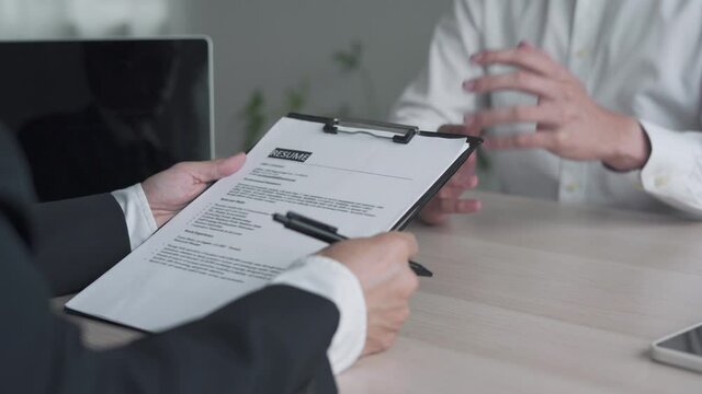 A business man's hand holding a resume. The management is taking the exam Candidate job interview.  Resume and interview concept.