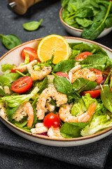 Shrimp salad with green leaves at stone table.