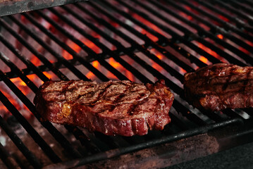 Juicy ribeye steak on a grilled. Brazier with fire. Fermented steak.