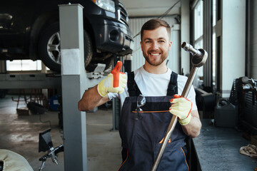 Auto mechanic standing in his workshop in front of a car