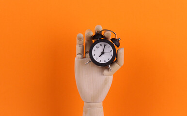 Clock in wooden hand on orange background