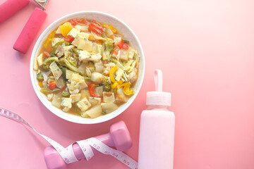 Fitness concept with dumbbell, fresh vegetable and measurement tape on pink 