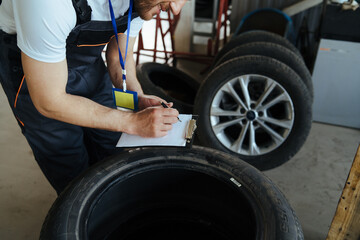 Obraz na płótnie Canvas Mechanic measuring depth of car tires in auto repair shop