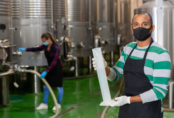 Man in protective mask with beaker in a winery shop