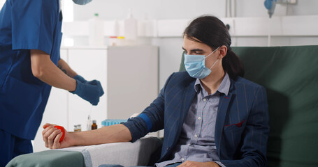 Fototapeta premium Portrait of young man donor in medical mask donating blood in laboratory.