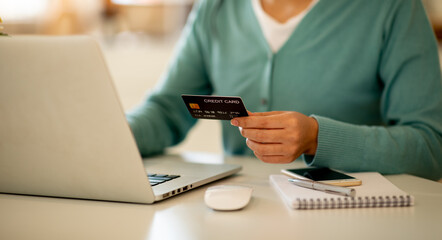 Close up woman hand using credit card and smartphone laptop for buying online shopping