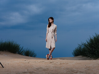 full-length portrait of a woman in a sundress and red sandals on the sand on the beach