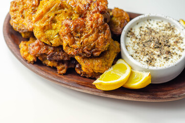 Delicious onion bhaji fritters served on wooden plate with white dip