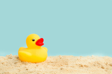 Fototapeta na wymiar Pato de goma amarillo en la arena de una playa. Vista de frente. Copy space