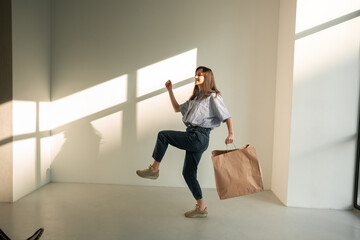 slender girl in jeans with a package of paper
young brunette girl holds a paper bag blue jeans stylish blouse stands and moves