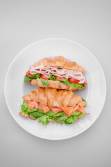 two beautiful croissants with salmon and ham isolated on a white plate. healthy breakfast. Top view
