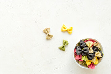 Italian farfalle pasta in bowl. Raw multicolored farfalle pasta, overhead view