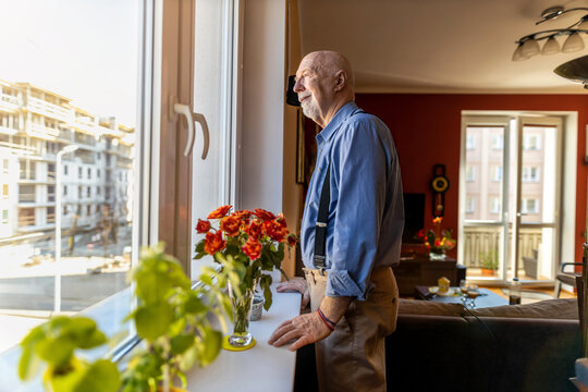 Senior Man Looking Through Window at Home