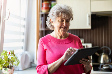 Fototapeta na wymiar Happy senior woman using digital tablet at home 