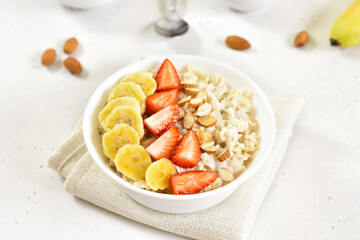Homemade oatmeal porridge with strawberry, banana and nuts