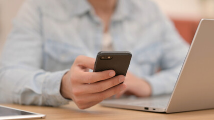 Male Hands Using Smartphone next to Laptop, Close up