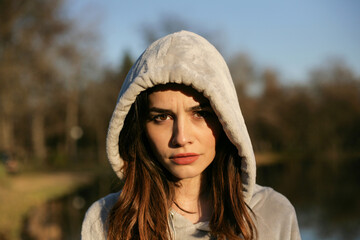 Portrait of a serious young woman with hood in nature.