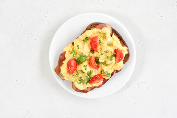 Scrambled eggs with microgreen and tomatoes on bread