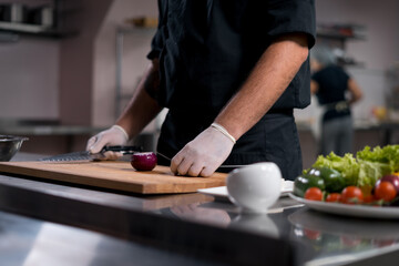 Fototapeta na wymiar chef cook in medical gloves prepare greek salad or chop vegetables at kitchen 