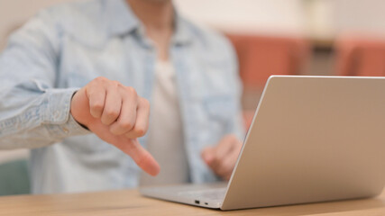 Man showing Thumbs Down while using Laptop, Close up