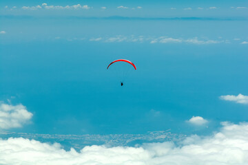 Paraglider flying in cloudy blue sky. Extreme sport. Landscape