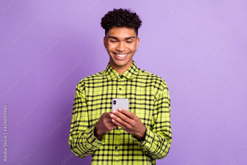 Sticker Photo portrait of guy cheerful holding smartphone reading news in internet isolated on pastel violet color background