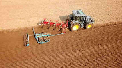 Traktor bearbeitet Feld mit Pflug und Grubber, Saatbettbereitung, Landwirtschaft aus der Vogelperspektive © keBu.Medien