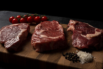 Raw marbled beef steak on a wooden cutting board. Top class marbled beef. Graphite-colored table top.