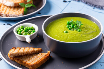 Fresh homemade peas cream soup with mint and toasted bread.