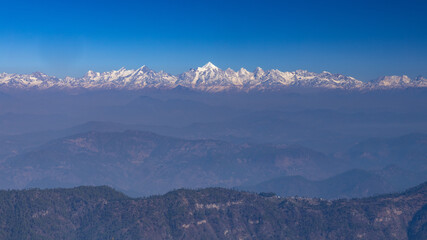 Fototapeta na wymiar Panoramic view of the snow covered Himalayan mountain ranges and Nanda Devi peak in the middle from a hill station called Almora in Uttarakhand India 