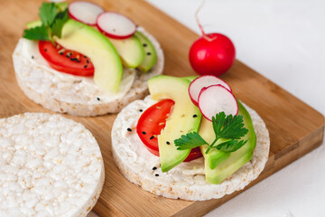 Fototapeta na wymiar Rice cake sandwich with cheese cream, avocado, tomato, radish and spices. A healthy dietary snack