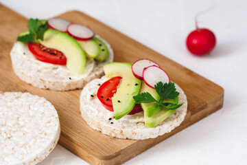 Rice cake sandwich with cheese cream, avocado, tomato, radish and spices. A healthy dietary snack