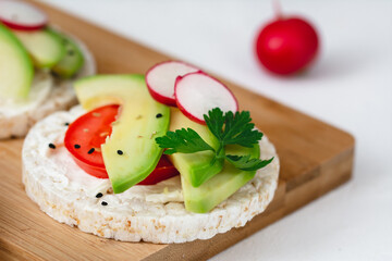 Rice cake sandwich with cheese cream, avocado, tomato, radish and spices. A healthy dietary snack
