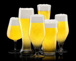 Set of fresh light beer glasses with bubble froth isolated on black background.