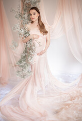 Beautiful and happy pregnant woman in floral decoration. Pregnancy. Happy mother. Future mother.