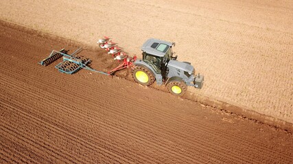 Traktor bearbeitet Acker mit Pflug und Grubber, Saatbettbereitung, Landwirtschaft aus der Vogelperspektive