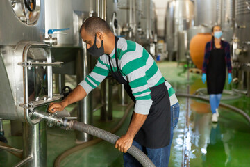Wine producer controlling production wine in winery, preparing for wine filtration