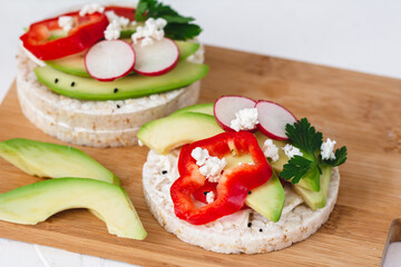 Rice cake sandwich with cheese cream, avocado, pepper, radish and spices. A healthy dietary snack