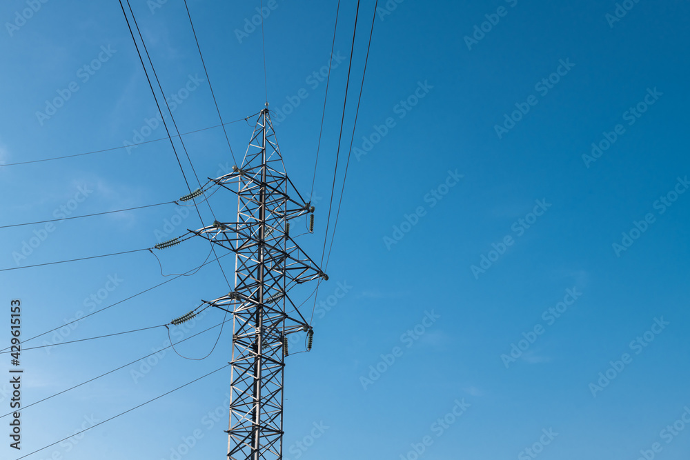 Wall mural high voltage tower against a blue sky and city background