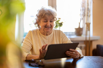Happy senior woman using digital tablet at home