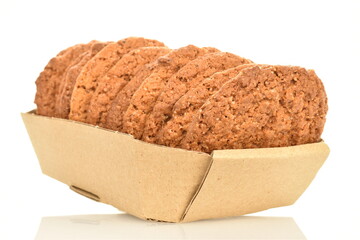 Several fragrant dark brown oatmeal cookies in a craft paper dish, close-up, isolated on white.