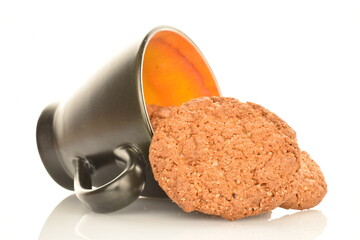 Three fragrant dark brown oatmeal cookies with a black ceramic cup, close-up, isolated on white.