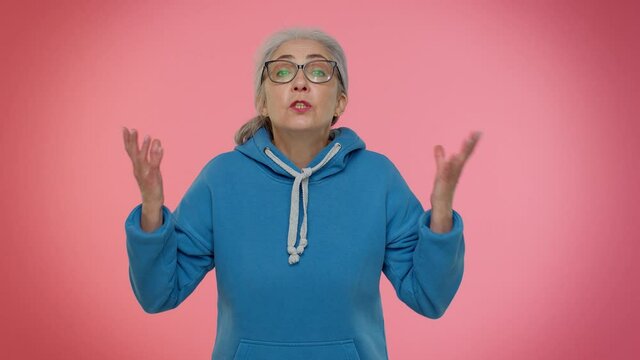 I cant believe. Why you did that. Upset annoyed elderly woman raising hands in indignant expression, quarreling, asking reason of conflict, why such stubborn. Senior old grandmother on pink background