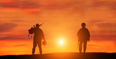 Naklejka na ściany i meble Military man and military woman on sunset background is symbol of equal rights.