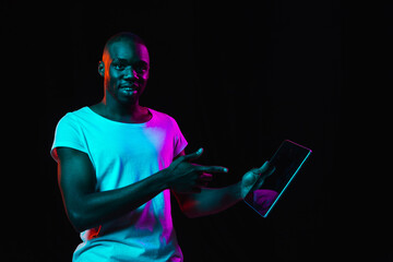 Young African-American man isolated on dark background in neon light