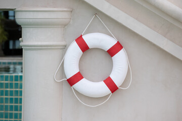 lifebuoy hang on white wall near pool.