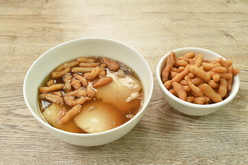 boiled soybean tofu pudding custard in ginger juice soup topping mini crispy fried Chinese dough in bowl on table