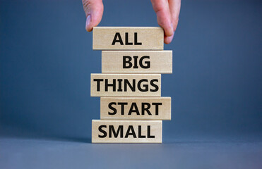 Business concept growth success process. Wood blocks on grey background, copy space. Businessman hand. Words 'all big things start small'. Conceptual image of motivation.