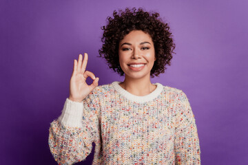 Happy young smiling african woman show okye sign with fingers isolated on violet background