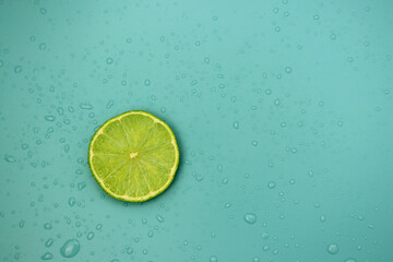 Slice of fresh lime on a blue background with water drops. Citrus background.